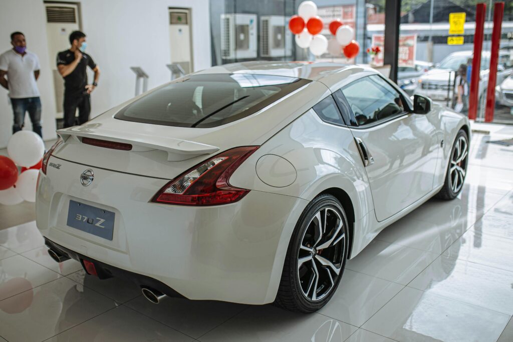 A gleaming white car sits on a pristine showroom floor, meticulously cleaned by Fort Worth cleaning professionals, showcasing its sleek design and spotless appearance under the bright, ambient lighting of the dealership.