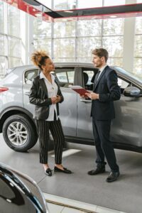 A salesman and a female customer standing beside a new car in a pristine Fort Worth car dealership showroom, professionally cleaned by Fort Worth Cleaning Professionals, reflecting the high standards of cleanliness and customer service.