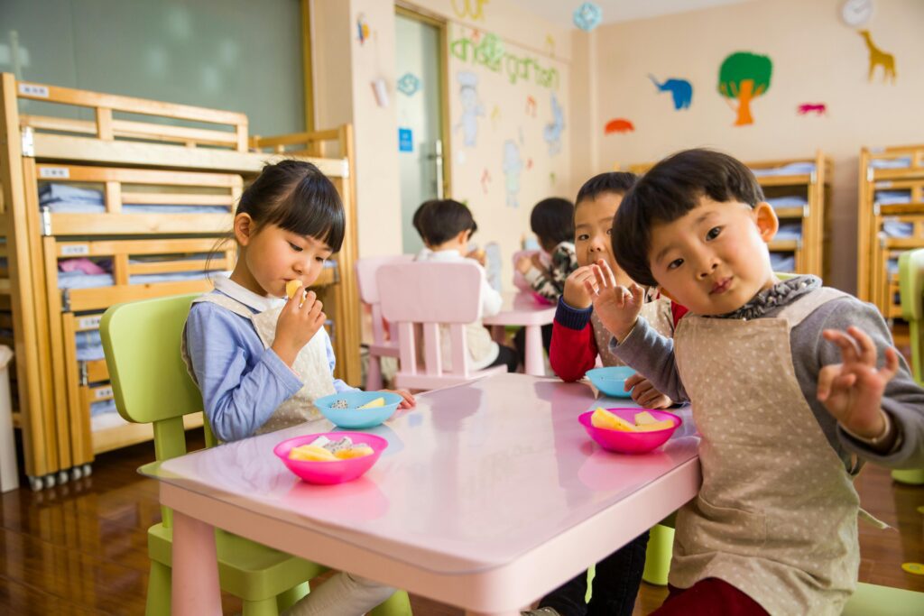 Children enjoying snack time together at a clean and organized daycare table, in a safe environment maintained by professional cleaning services.