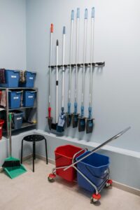 Supply closet setup for janitorial teams: color-coded microfiber bins, wall-mounted mops, and a dual-bucket system arranged for fast, safe cleaning.